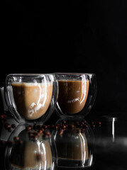 Coffee in a glass, on a black background, from coffee beans. Morning