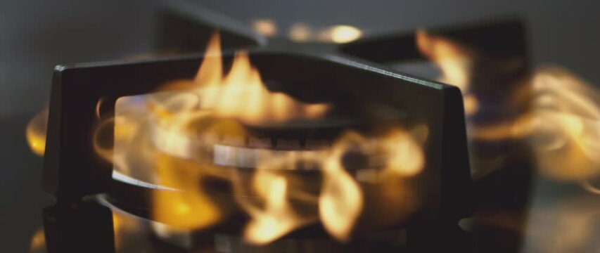 Kitchen burner turning on in 1000fps slow motion. Stove top burner igniting into a blue cooking flame. Natural gas inflammation, close up.
