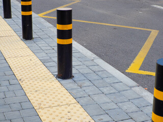 Yellow pavement for the blind on the floor on the bus stop with road bollards