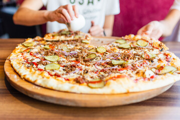 Someone young people takes pizza in pieces in a pizzeria.