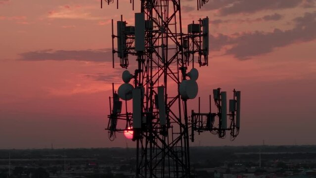 Television or radio telephone tower in a cityscape at sunset time. Aerial zoom view