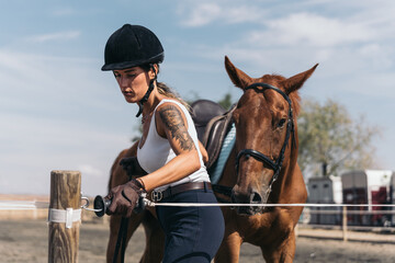 Young jockey inside the training enclosure of the equestrian center with his horse. Middle-aged...