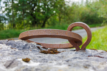 Metal ring and eye fixed to a large heavy bolder rock climbing anchor point