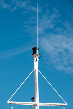 A metallic nautical light pole against a bright blue sky. Maritime radio antenna installation on the ship.