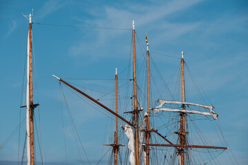 Collection of tall wooden sail masts against a bright blue sky.