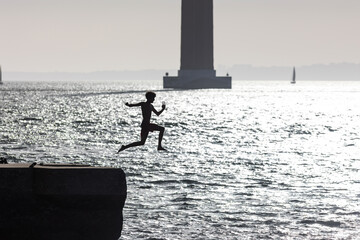 A boy jumps into the water with a takeoff run - monochrome image