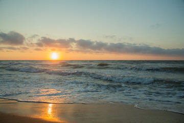 Fototapeta na wymiar Sunrise from behind the sea, golden water and the edge of the coast.