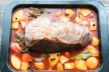 braten sauerbraten bierbraten auf einem backblech mit sauce am stück