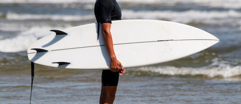 Man holding white surfboard with the ocean in the background