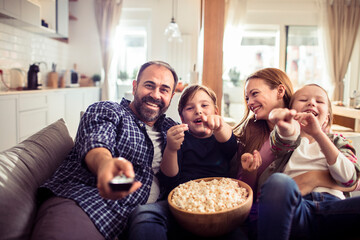 Young Caucasian family watching a movie and having fun on the couch in the living room at home