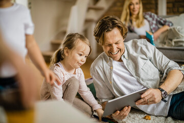 Young Caucasian father having fun on the tablet with her daughter at home