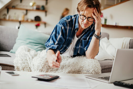 Stressed Middle Aged Man Going Over Bills In The Living Room At Home