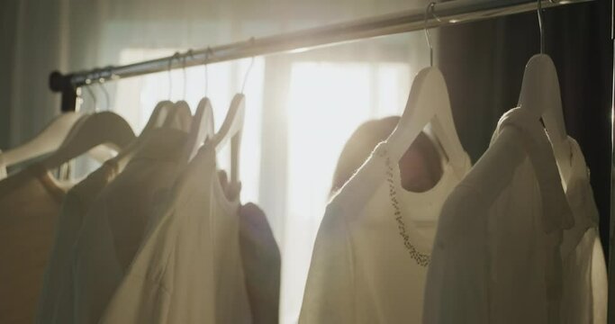 A woman chooses clothes in the dressing room. Silhouette in the sun, side view
