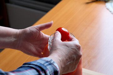 The hands of an elderly woman take out delicious homemade pickled tomatoes