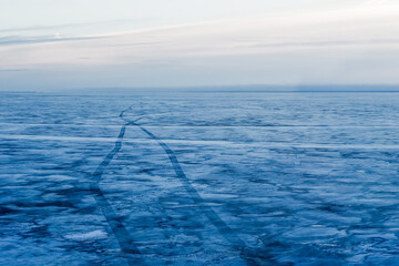 Winter arctic tale on sunset. Frozen big lake in winter, path on ice, traces from hovercraft - 650832485