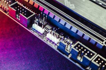 Motherboard with connectors and microchips close-up on modern desktop PC in vivid light. Computer hardware chipset components. Tech electronics background