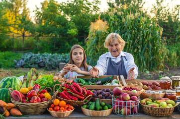 Grandmother and granddaughter sell vegetables and fruits at the farmers market. Selective focus.