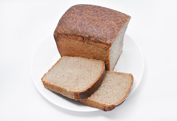 A black loaf of bread cut on a white plate. Slices of bread. Breakfast from a bun.