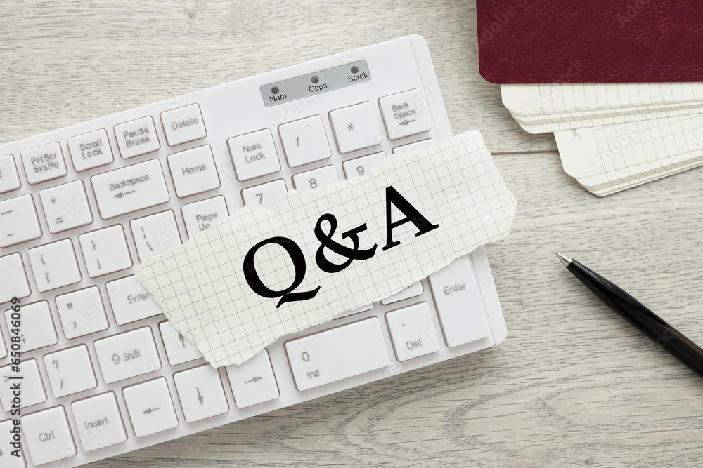 Poster q and a white keyboard on the desktop.torn paper text
