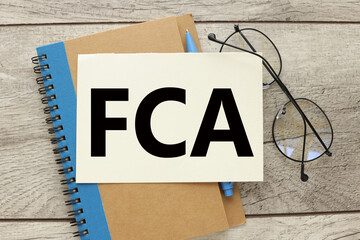 FCA - Financial Conduct Authority notebook with a blue stripe and glasses on the notebook.