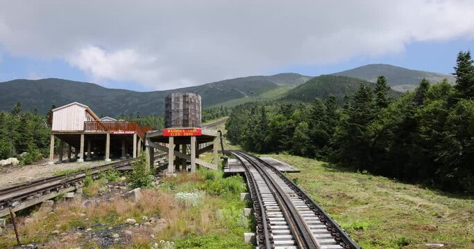 A cog railway train passing a water stop on mount Washington Waumbek station