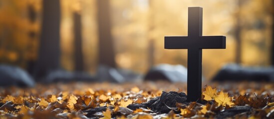 Autumn cemetery with a black cross on a headstone made of granite - obrazy, fototapety, plakaty