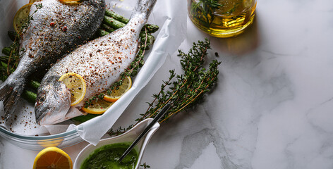the concept of a delicious dinner for two from dorado. raw baked dorado fish with asparagus and lemon in spices