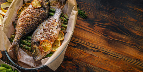 the concept of a delicious dinner for two from dorado. baked dorado fish with asparagus and lemon in spices