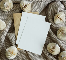 Cards mockup, envelopes, christmas garland and beige knitting plaid top view background. copy...