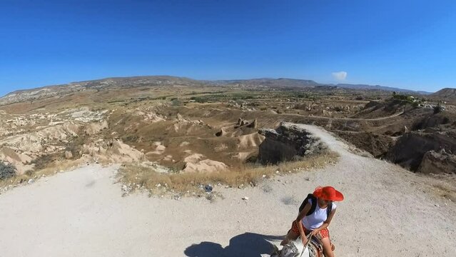 A tourist woman riding horse and enjoying the panoramic view of Devrent Valley unique rock sculptures, revealing the ethereal beauty of Cappadocia's landscape in Turkey