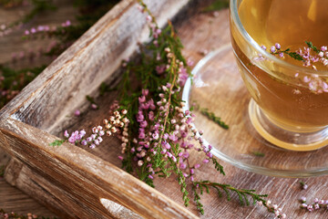 Obraz na płótnie Canvas Heather flowers with a cup of herbal tea on a table