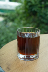 Glass cup with coffee from drip bag on wooden table. Trends in making coffee at home.