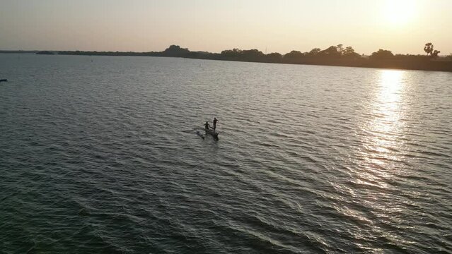 Aerial footage of traditional fishing boats in a large lake, depicting rural village life during the evening sunset.