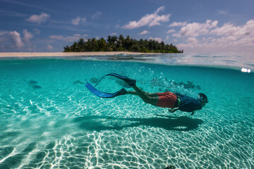 attractive young man snorkels in the ocean and observes the coral world, free diver in the sea, coral reefs in the Maldives