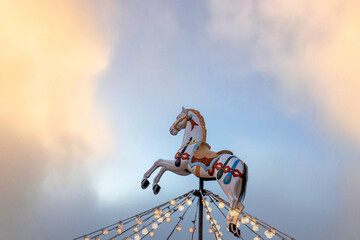 Detail of a wooden white horse on top of a children’s carousel against sunset sky, San Vincenzo, Livorno, Tuscany, Italy