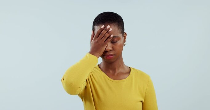 Facepalm, fail or mistake with a frustrated black woman in studio on a blue background feeling annoyed. Stress, emoji or error and an unhappy young person in crisis with a problem, regret or worry