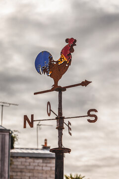 vintage weathercock in the shape of a colorful rooster on a French roof