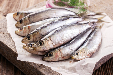 Fresh raw European sardines offered as close-up on stone design tray