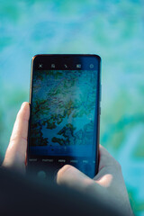 Vertical shot of a hand holding a smartphone and taking a photo of a map