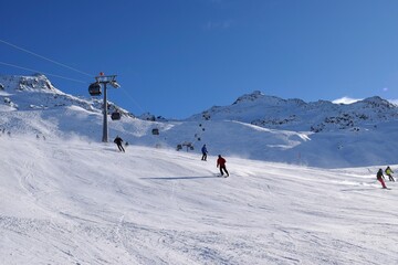 Downhill skiers in Hochgurgl ski resort on a beautiful sunny day, perfect conditions for winter sport, skiing and snowboarding in the snow capped alpine mountains in the Ötztal valley, Tyrol, Austria.