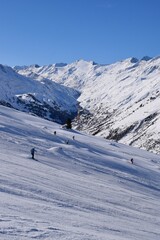Fototapeta na wymiar Skiers and snowboarders in Hochgurgl ski resort, backdropped by the Ötztal valley and the snow capped alpine mountains in Tyrol, Austria on a beautiful sunny day, perfect conditions for winter sports.