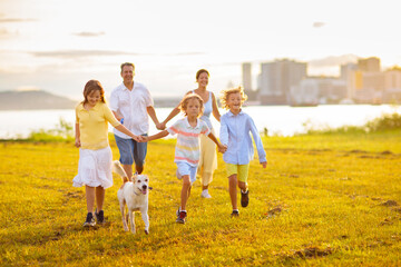 Family with kids running outdoor at sunset.