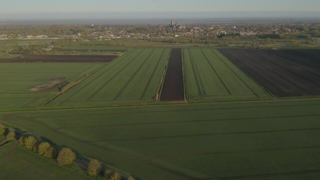 Aerial fly over crop fields approach historical landmark - Ely cathedral in Cambridgeshire, England, UK. Famous travel destination and anglican churches concept