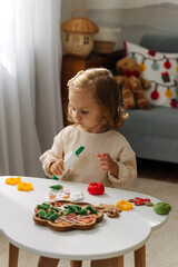 A little girl playing with play dough and Christmas decorations. Child hands creating Christmas crafts. Holiday Art Activity for Kids. Sensory play for toddlers.
