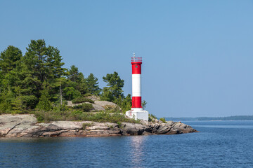 A Red and White Lighthouse on a Rocky Point of Land on Clear Blue Sky Summer Day in Parry Sound, Lake Huron, Georgian Bay, Ontario, Canada - 650884619