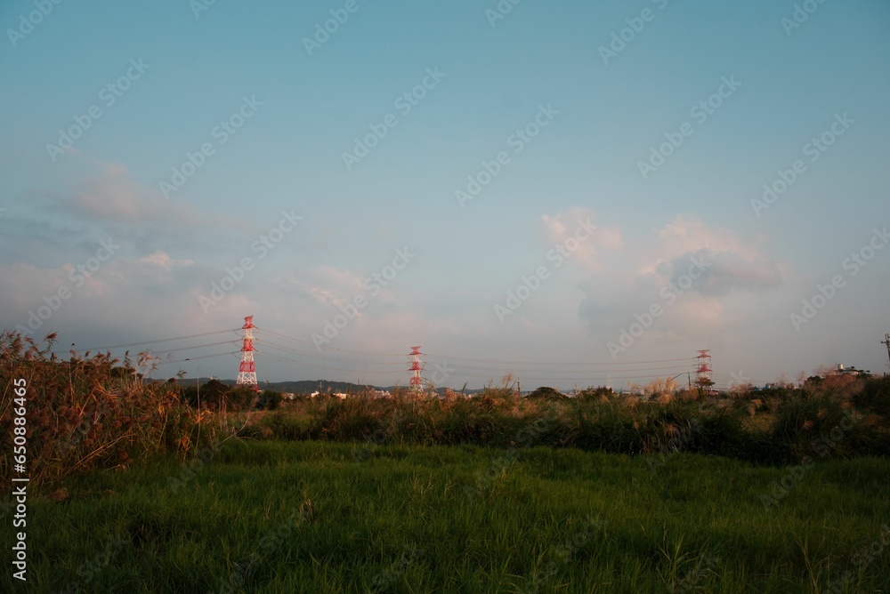 Poster idyllic landscape featuring red power lines extending across a rolling grassy field