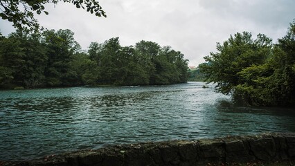 Scenic view of the Krka River in Slovenia with a wide riverbank and lush greenery in the background