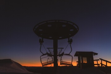 the sun sets behind a ski lift on a mountain side