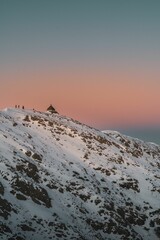 Group of hikers on slope of a mountain covered with snow at sunset
