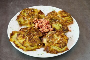 White plate featuring a freshly cooked dish of artichokes with grilled ham